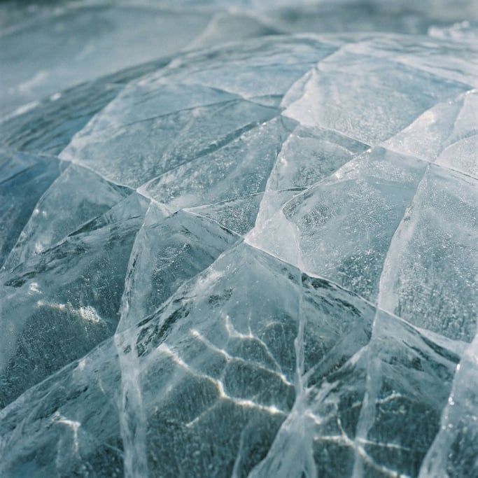 Ice sheet cracking, blue-white fracture lines across a frozen surface, abstract geometry