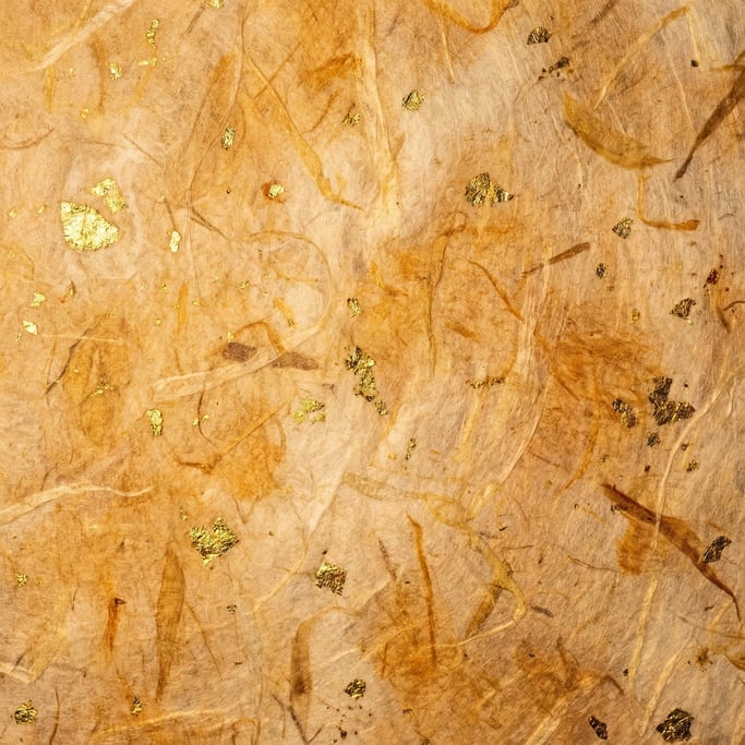 Japanese washi paper with embedded gold leaf flecks, translucent fibers, handmade quality