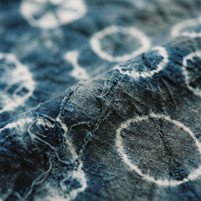 Shibori-dyed indigo fabric, resist patterns creating organic white shapes on deep blue