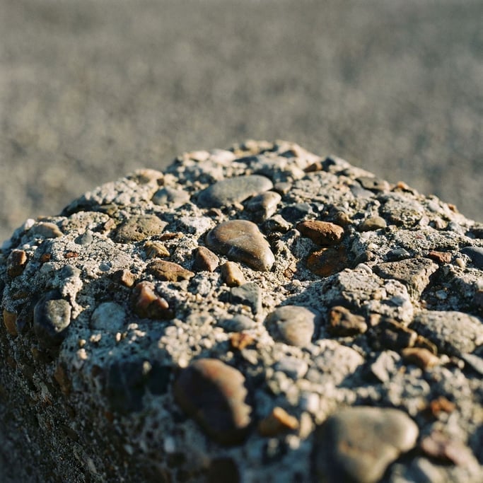 Extreme close-up of Raw concrete with exposed aggregate, stones and pebbles set in gray cement