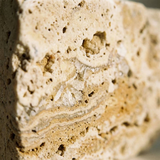 Extreme close-up of Raw travertine limestone with natural voids and layered mineral deposits