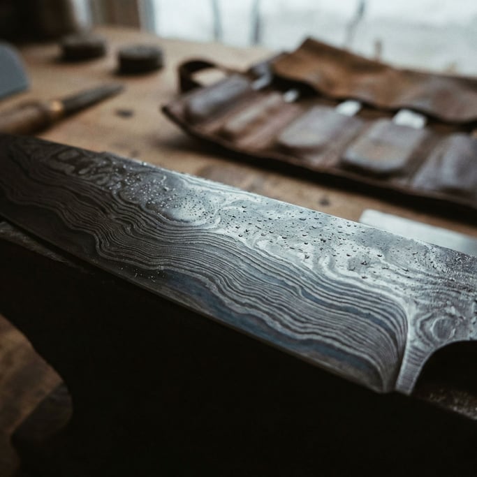 Detail photograph of Hand-forged Damascus steel blade pattern, wavy layers of folded metal