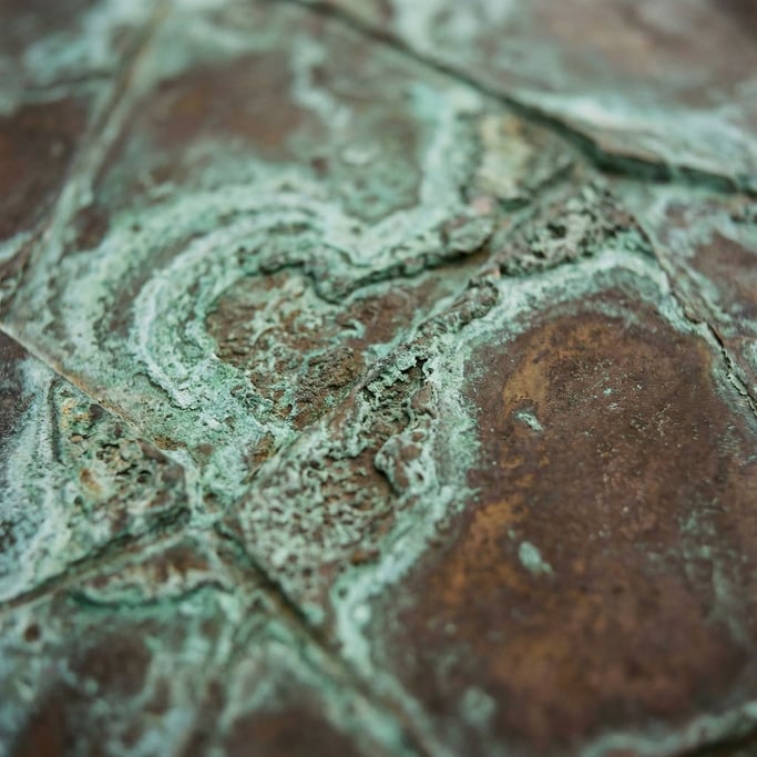 Oxidized bronze sculpture surface, verdigris green fading into warm brown patina