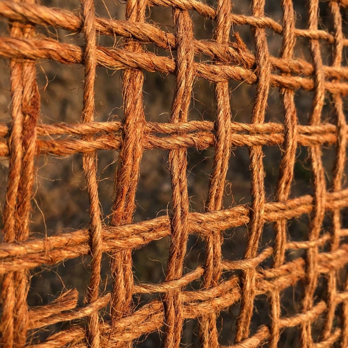 Burnt-orange burlap weave dominating the composition with its coarse jute grid