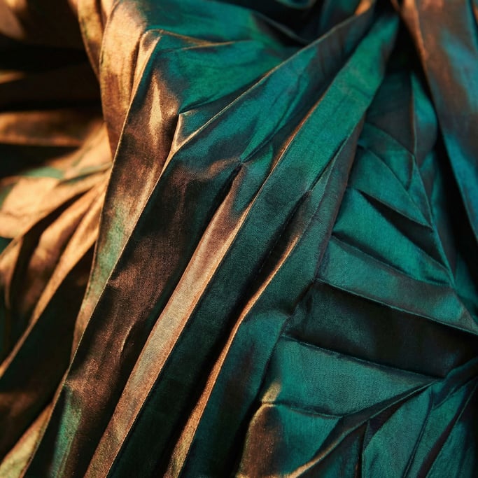 Teal shot-silk taffeta captured at macro scale with crisp angular folds