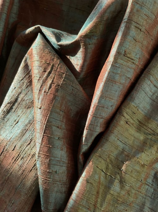 Oxidized-copper toned silk dupioni dominating the composition with its characteristic slubby crosswi