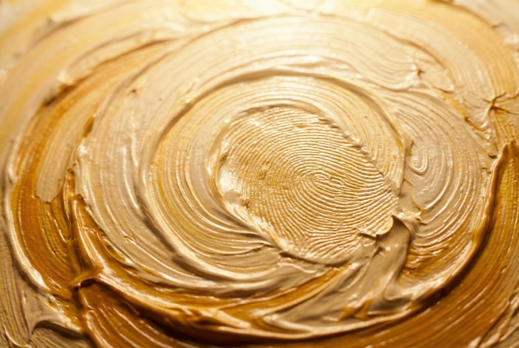 Naples yellow oil paint applied with fingers in circular swirling patterns filling the frame