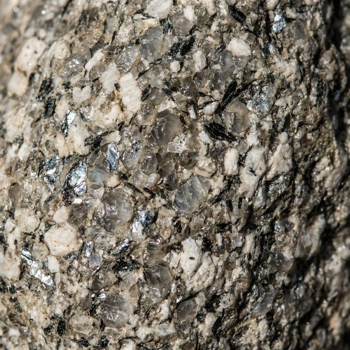 Rough granite surface in close-up shot tight with no border, the three minerals — glassy quartz