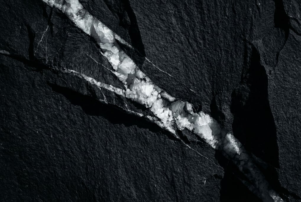 Black basalt with a single vein of white calcite cutting diagonally across the frame