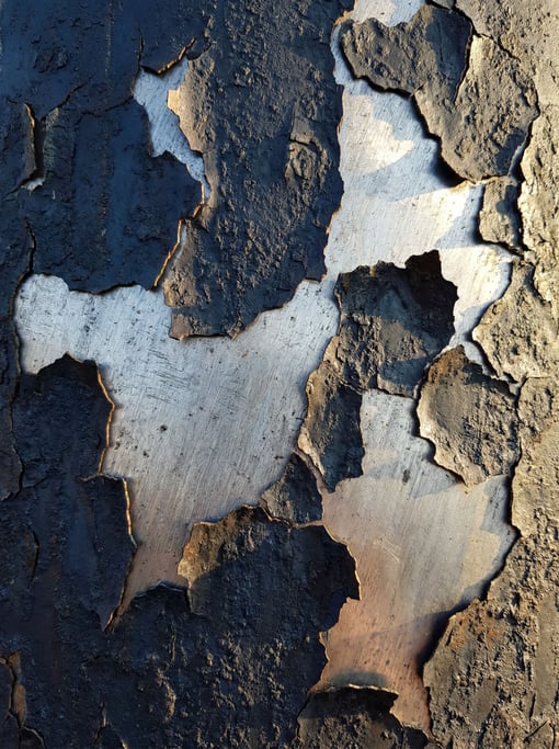 Patinated iron with mill scale flaking to reveal bright steel beneath