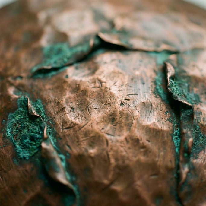 Extreme close-up of Hammered copper sheet with dents and oxidation turning green at the edges (3uiyesg)