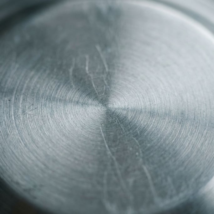 Extreme close-up of Brushed stainless steel with circular polishing marks, cool industrial surface (omvfvut)