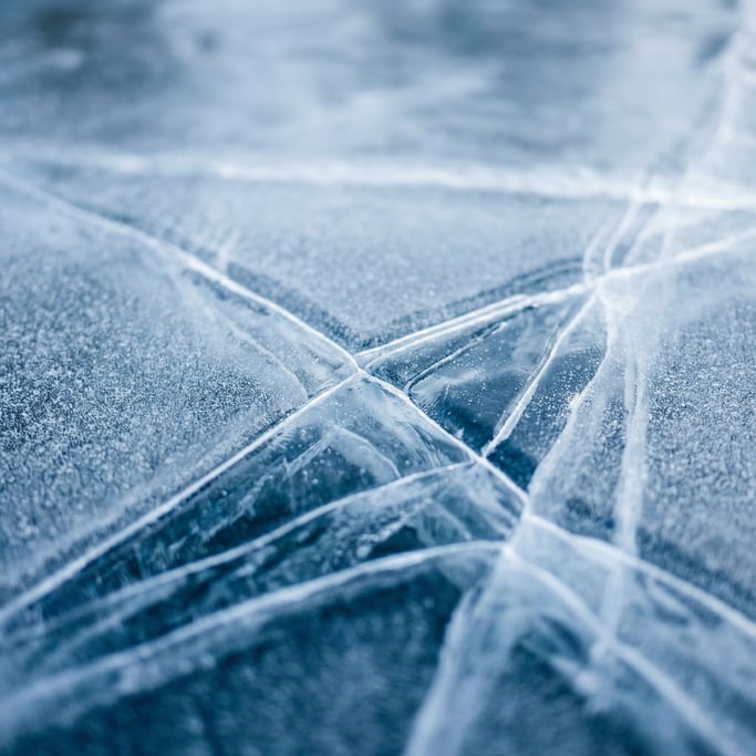 Extreme close-up of Ice sheet cracking, blue-white fracture lines across a frozen surface (pqtgpfv2)