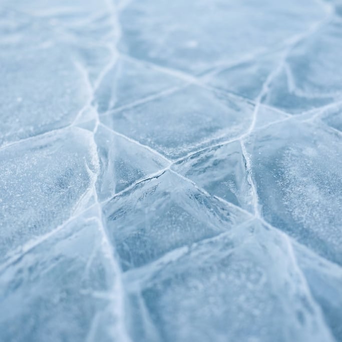 Extreme close-up of Ice sheet cracking, blue-white fracture lines across a frozen surface (gc7z1ajk)