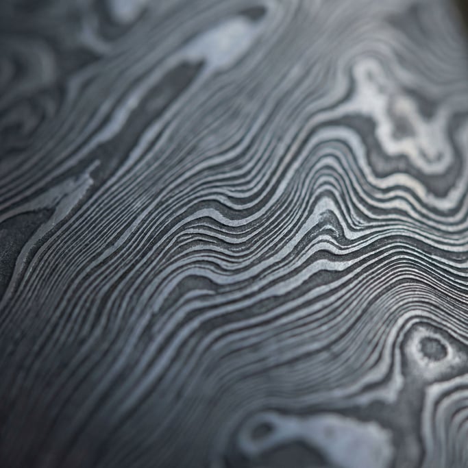 Hand-forged Damascus steel blade pattern, wavy layers of folded metal, etched and polished