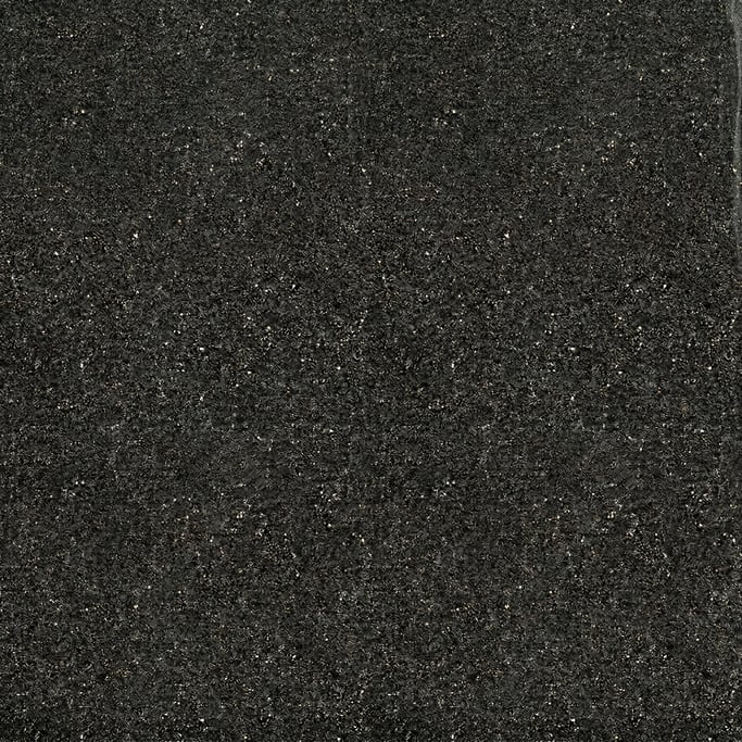 Seamless tileable texture of black volcanic sand heavily worn and patinated