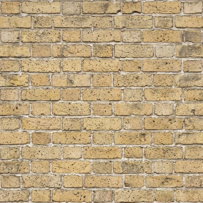 Seamless tileable texture of yellow London stock brick heavily worn and patinated