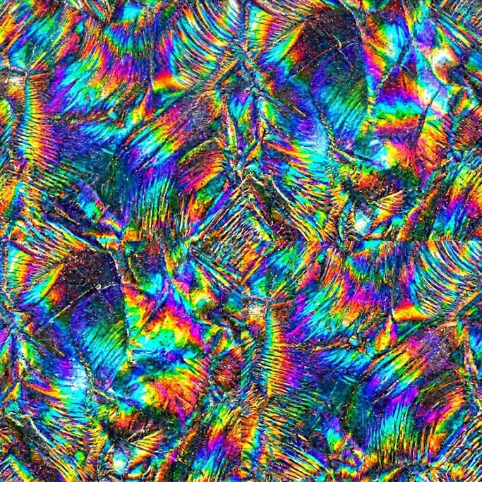 Seamless tileable texture of holographic foil in extreme close-up showing micro-detail