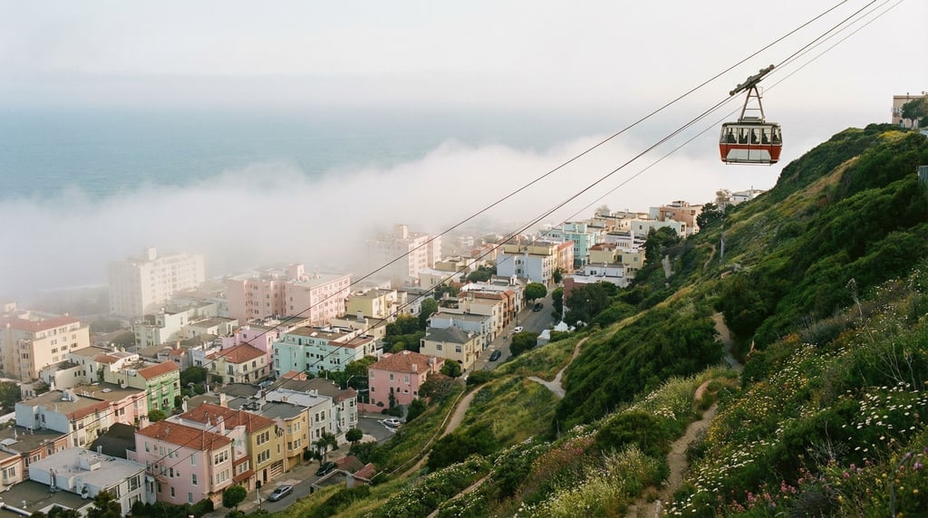 Cable car ascending a steep green hillside above a coastal city, fog rolling in from the sea