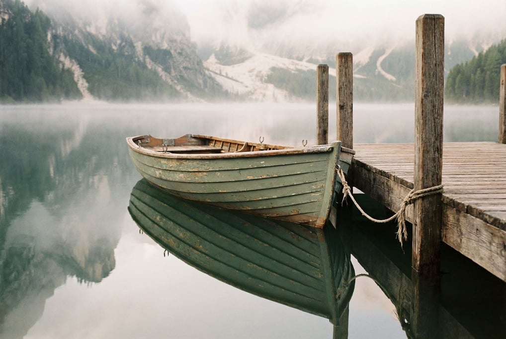 Weathered rowboat tied to a wooden dock on a still mountain lake
