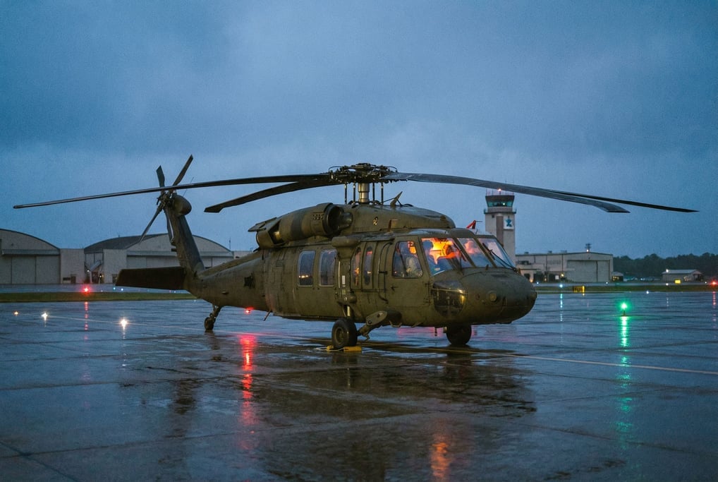 Military helicopter in olive drab on a tarmac at dusk, rotor blades drooping at rest