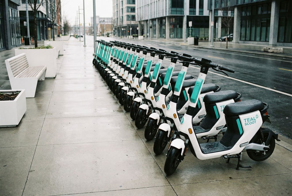 Row of identical rental scooters parked on a sidewalk, clean modern design in white and teal