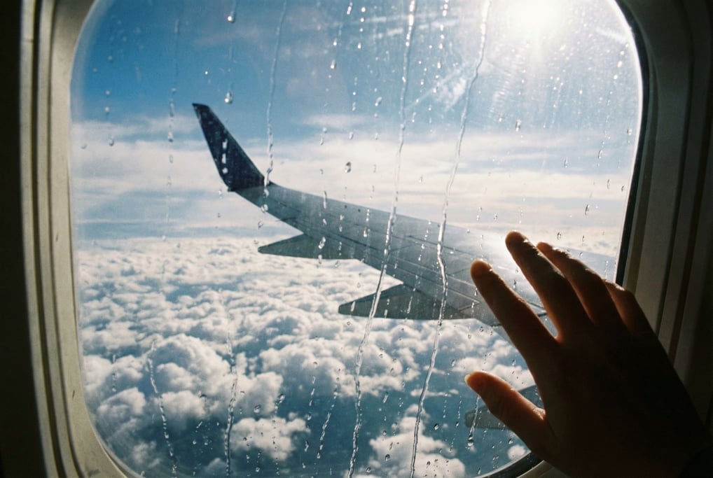View through a rain-streaked aircraft window at thirty thousand feet, wing visible below