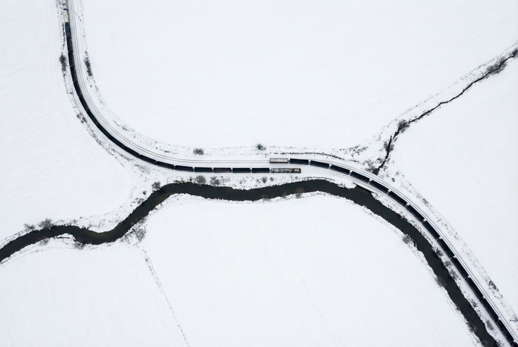 Aerial view of a freight train snaking through a snowy landscape
