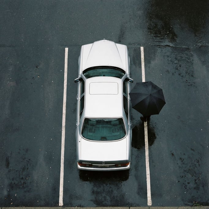 Top-down view of a silver sedan on a rain-wet parking lot
