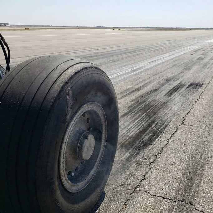 Aircraft tire on a runway, the tread pattern worn smooth in the center from landings