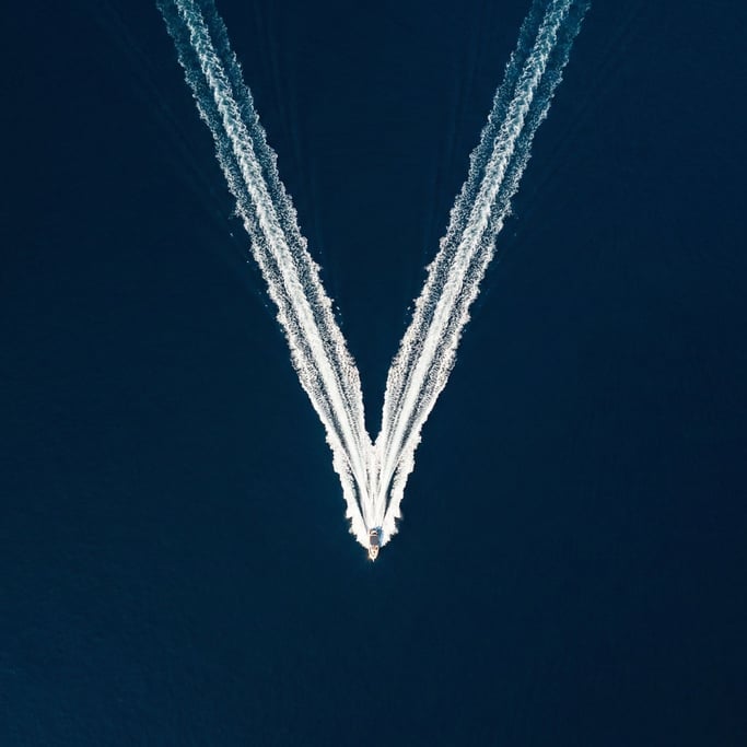 Drone shot of a single boat wake forming a white V on dark blue ocean