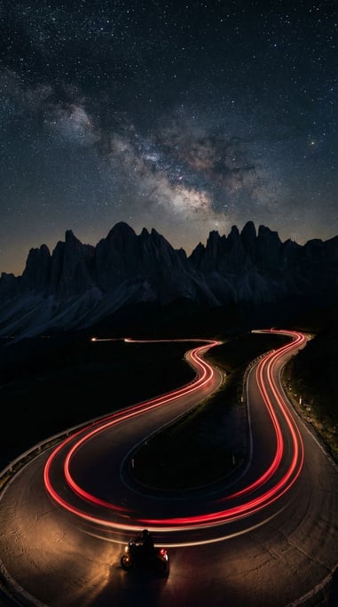 Motorcycle taillight trail on a winding mountain road at night