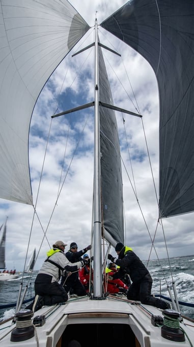 Sailing yacht mast from the cockpit looking up during a race, sails billowing