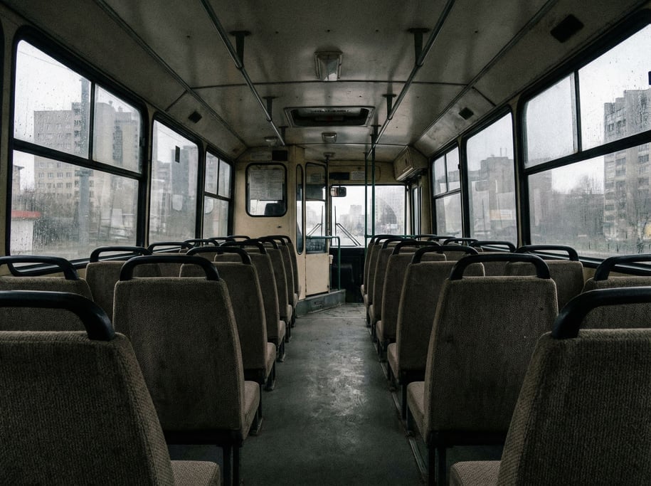 Bus interior from the back seat, rows of empty seats leading to the driver's area