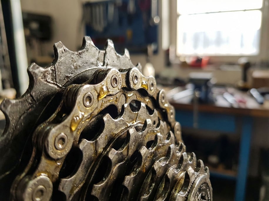 Close-up of a bicycle chain on the rear cassette, oil glistening on the links and sprocket teeth