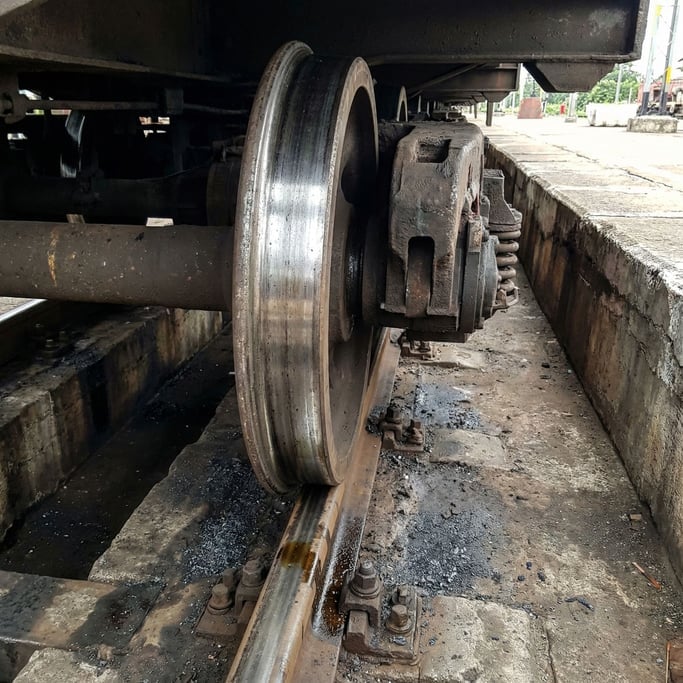 Train wheel and track close-up at platform level, the massive steel wheel on the polished rail