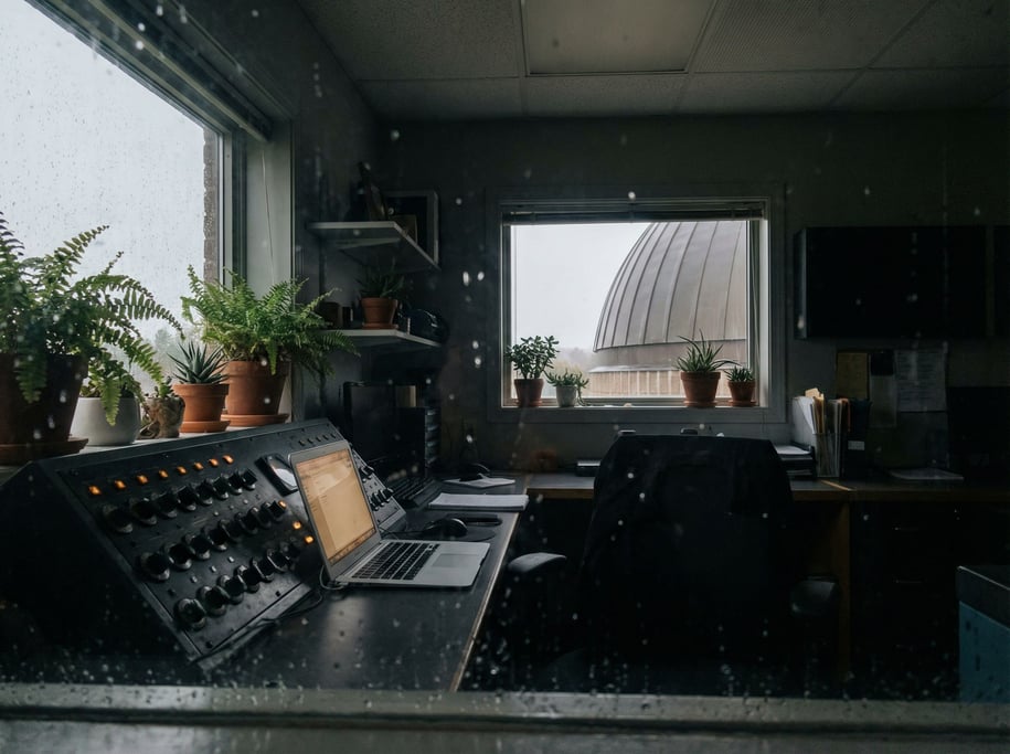 A planetarium control room, laptop next to a bank of dimmed switches (bk1jcbiq)