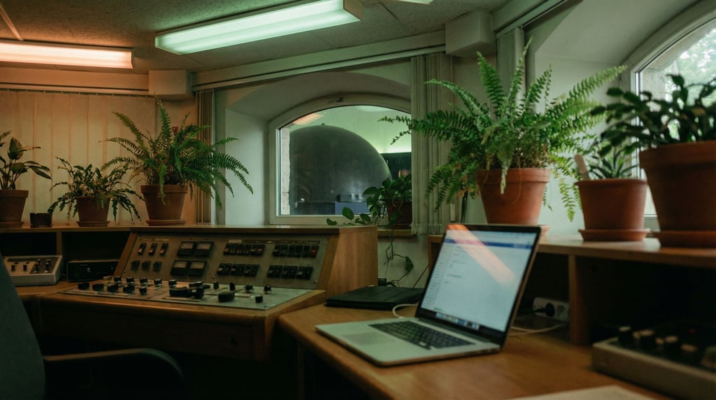 A planetarium control room, laptop next to a bank of dimmed switches (sh8ntzre)