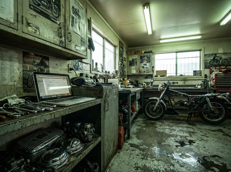 A motorcycle garage office corner, laptop on a metal shelf unit (rzfoh3ry)