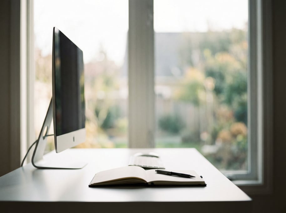 An empty minimal desk with just a closed laptop and a glass of water, clean white walls (d7j53)