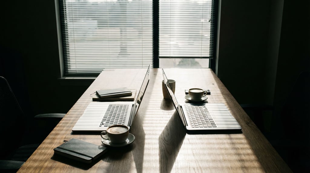 A shared modern coworking table with two laptops facing each other, flat whites between them (skprb3m3)