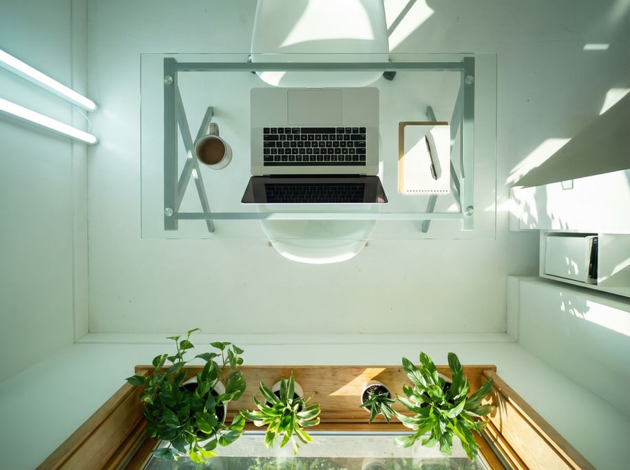 A bright airy studio with white walls, large windows, a glass desk with a slim laptop (hdrb1)