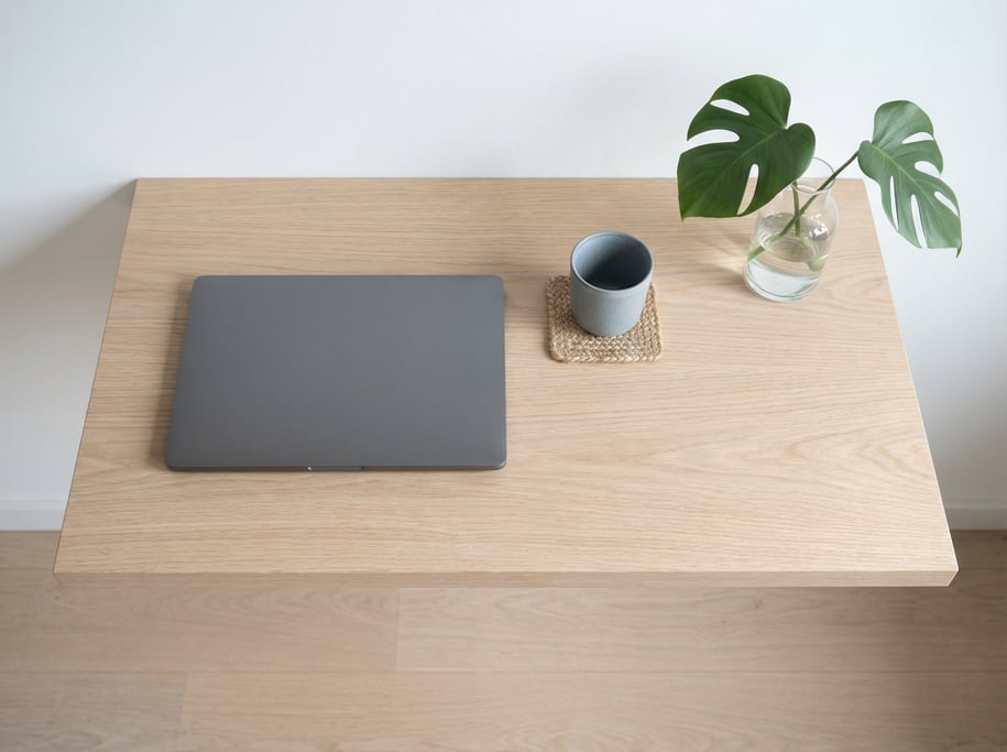 Overhead bird's-eye view looking directly down at a clean cantilevered wall-mounted desk in pale oak