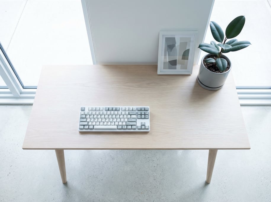 Overhead bird's-eye view looking directly down at a clean clean white oak desk with tapered legs sur