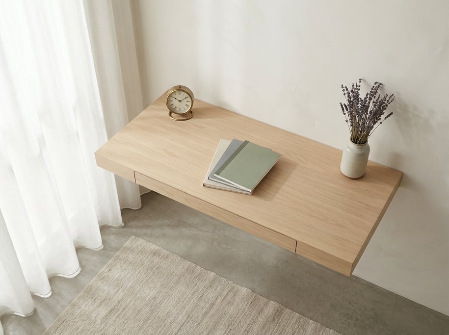 Overhead bird's-eye view looking directly down at a clean cantilevered wall-mounted desk in pale oak